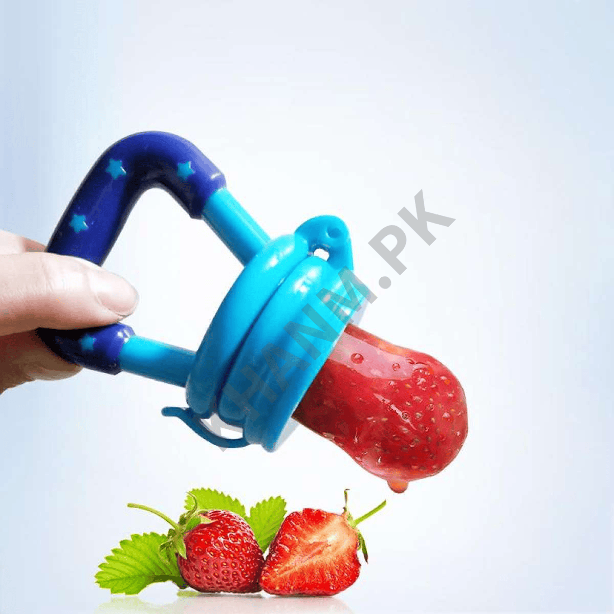 Blue fruit feeder with a strawberry attached, held by a hand on a light blue background.