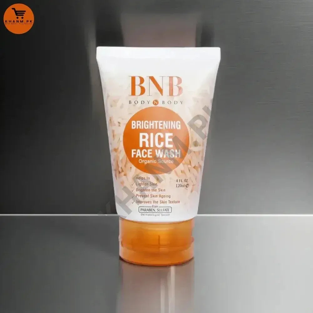 Tube of BNB Brightening Rice Face Wash on a reflective surface with a gray background