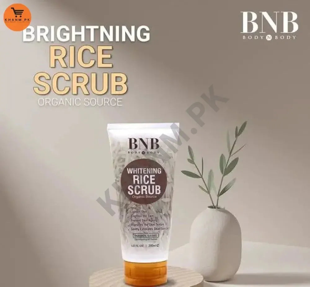 Tube of BNB Brightening Rice Scrub with a plant on a neutral background